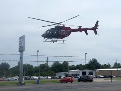 Red helicopter hovering over parking lot.