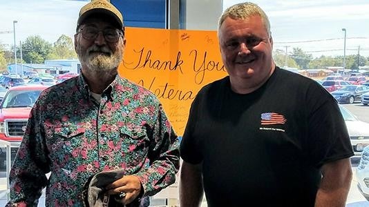 Two men smiling near a sign